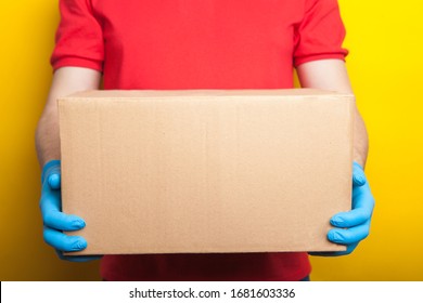 home delivery, online order. A man in uniform, a medical mask and rubber gloves with a box, a parcel in his hands. Food and food delivery during the quarantine of the coronavirus pandemic