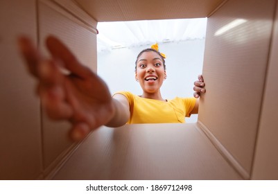 Home Delivery Service And Unboxing Concept. Happy and excited african american woman unpacking carton box and looking inside, trying to get goods outside. View from the package on overjoyed black lady - Powered by Shutterstock