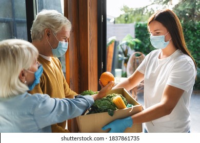 Home Delivery Service Young Woman Handing Fresh Food In Cardboard Box To Adult Couple. Donation Or Online Food Delivery Concept