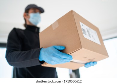 Home delivery shopping box man wearing gloves and protective mask delivering packages at door. - Shutterstock ID 1710550612