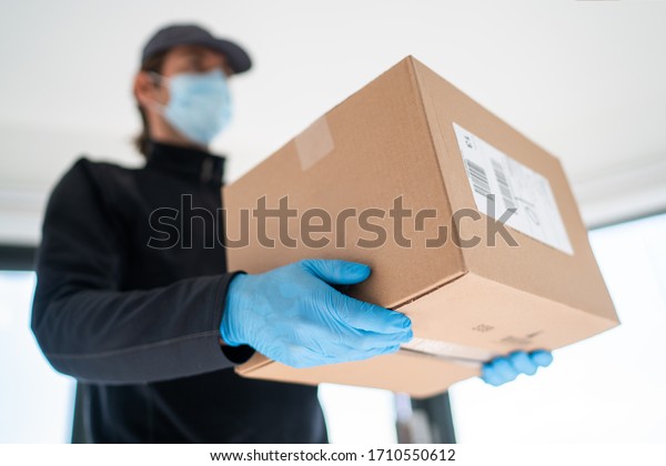 Home delivery shopping box\
man wearing gloves and protective mask delivering packages at\
door.