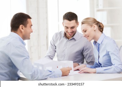 Home, Design And Architecture Concept - Couple Looking At Blueprint And Model Of Their New House At Office