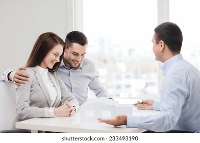 Home, Design And Architecture Concept - Couple Looking At Blueprint And Model Of Their New House At Office