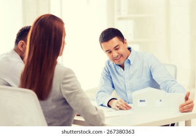 Home, Design And Architecture Concept - Couple Looking At Blueprint And Model Of Their New House At Office