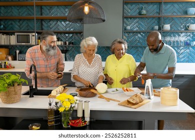 At home, Diverse group of senior friends preparing vegetables together in modern kitchen. Friendship, cooking, healthy eating, seniors, togetherness, lifestyle, unaltered - Powered by Shutterstock