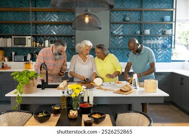 At home, Diverse group of senior friends preparing food together in modern kitchen. Cooking, friendship, seniors, lifestyle, teamwork, healthy eating, unaltered - Powered by Shutterstock