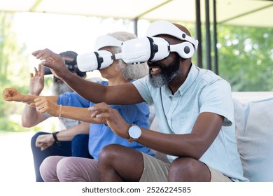 At home, Diverse group of seniors using VR headsets, enjoying virtual reality experience. Technology, entertainment, enjoyment, innovation, unaltered - Powered by Shutterstock