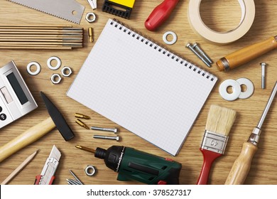 Home DIY And Improvement Concept, Blank Notebook With Work Tools All Around On A Wooden Table, Top View