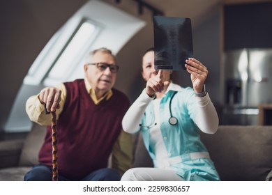 Home doctor is examining x-ray image with old man at his home. Professional health support for elderly people. - Powered by Shutterstock