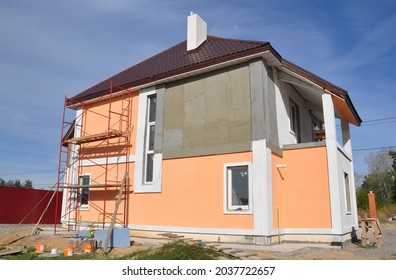 Home Exterior Renovation And Outside House Walls Painting. A Close-up Of A House Under Renovation With Scaffolding For Rendering, Plastering And Painting.