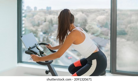 Home Fitness Workout Woman Training Cardio On Bike Cyle With Online Gym Class Streaming. Girl Biking On Stationary Bicycle Indoor.