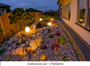 Home garden at night, illuminated by globe shaped lights. Decorative gardening and landscaping abstract. Lush May foliage.