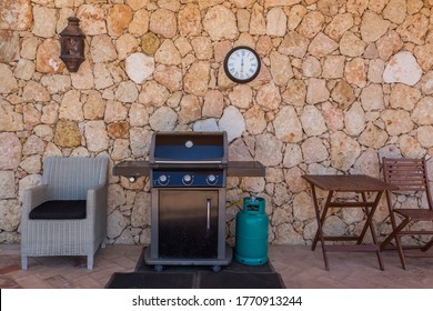 Home Gas Grill With Cylinder, For Family Holidays And Dinners. In The Yard Near The Wall.