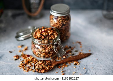 Home granola in a glass jar. Selective focus, concrete background.Healthy vegan snack