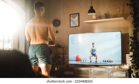 Home Gym Training: Handsome Muscular Black Man Using Kettlebell, Does Endurance Exercise. Strong Mixed Race Sportsman Workout Watching Fitness Coach on Streaming Platform. Back View Angle Shot - Powered by Shutterstock