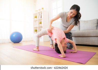 Home Gymnastics Teacher Assist The Beautiful Children Doing Yoga Action And Hands Helping Holding Kids Body Waist Careful Prevent Injury In The Sporting Studio.