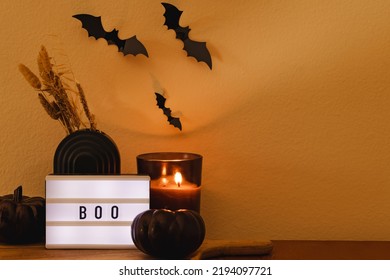 Home Halloween Decor Composition With Candle, Black Pumpkin, Bats And Light Box With Text Boo