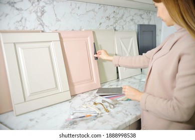 Home improvement concept. Girl the designer chooses the facades and handles for cabinet furniture in a store showroom. decors boards on the furniture industry. Choosing samples of materials.