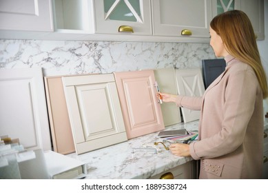 Home Improvement Concept. Girl The Designer Chooses The Facades And Handles For Cabinet Furniture In A Store Showroom. Decors Boards On The Furniture Industry. Choosing Samples Of Materials.