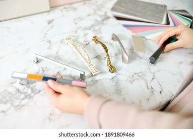 Home Improvement Concept. Girl The Designer Chooses The Facades And Handles For Cabinet Furniture In A Store Showroom. Decors Boards On The Furniture Industry. Choosing Samples Of Materials.