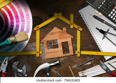 Home Improvement Concept - Wooden Model House With Folding Ruler, Work Tools And A Calculator On A Wooden Desk