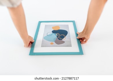 Home Improvement, Decoration And People Concept - Close Up Of Hands Hanging Picture In Frame On Wall