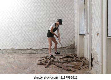 Home Improvement And DIY Project. Young Woman Is Removing Old Wooden Parquet Flooring Using Crowbar Tool. Old Wooden Floor Renovation.	