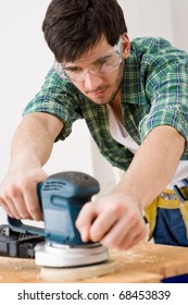 Home Improvement - Handyman Sanding Wooden Floor In Workshop