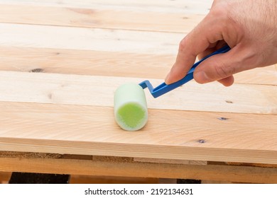 Home Improvement-a Handyman Varnishes A Wooden Homemade Table, Holds A Plastic Roller With A Foam Nozzle In His Hand.