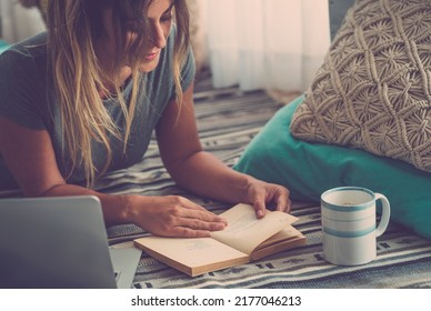 Home Indoor Leisure Activity People. Young Happy Alone Woman Reading A Book And Use Laptop Laying Onthe Carpet. Female Enjoy Time And Sunday Studying And Relaxing. House Lifestyle Girl Portrait