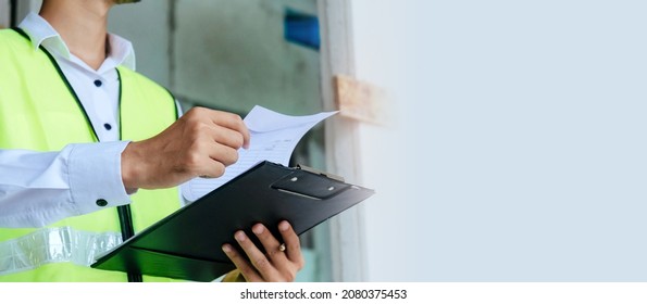 Home Inspector Engineer In Green Reflective Jacket Checking Review Document And Inspecting With Clipboard At Construction Site Building Interior, Construction, Contractor And Engineering Concept