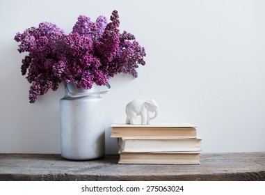 Home interior decor, bouquet of lilacs in a vase and books on rustic wooden table, on a white wall background - Powered by Shutterstock