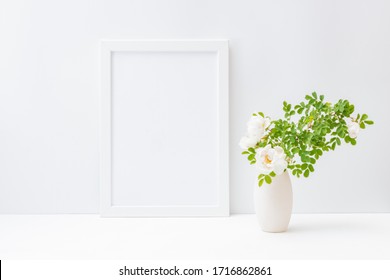 Home Interior With Decor Elements. Mockup With A White Frame And Small Flowers And Green Leaves In A Vase On A Light Background