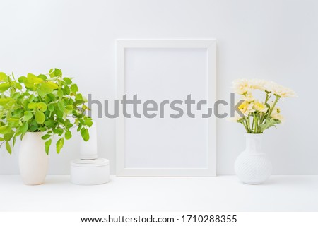 Home interior with decor elements. Mockup with a white frame and flowers in a vase on a light background
