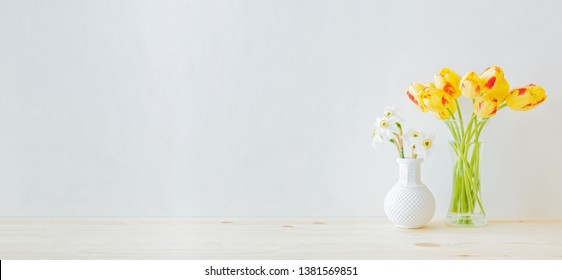 Home interior with decor elements. Yellow tulips in a glass vase on a wooden table