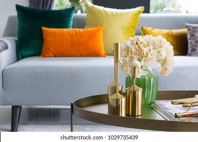 Innendekorative Einrichtung auf Tisch mit Glaskeramik und getrockneten Blumen, Kerze.  Farbige Kissen auf grauem Sofa.