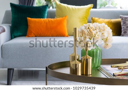 Home interior decorative item on table with glass jar and dried flowers, candle.  Colorful cushions on grey sofa.