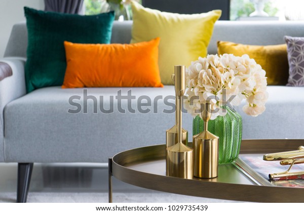 Home interior\
decorative item on table with glass jar and dried flowers, candle. \
Colorful cushions on grey\
sofa.