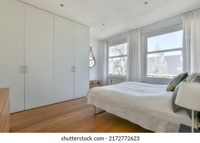 Home interior design of bedroom with bed and wooden wardrobe placed in corner near window in modern apartment - Shutterstock ID 2172772623
