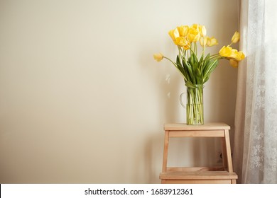 Home interior design, bouquet of yellow tulips on wooden stool