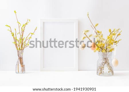 Home interior with easter decor. Mockup with a white frame and willow branches in a vase on a light background