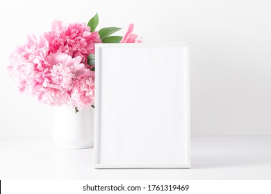 Home Interior Floral Decor On White Shelf. Front View Blank Mock Up Of Photo Frame. Beautiful Flowers Pink Peonies In Vase On White Background.