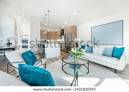 Home interior showing kitchen dining and living room decorated with blue and turquoise aqua colors white sofa round coffee table granite marble island with bar stools rectangle dining table with chair