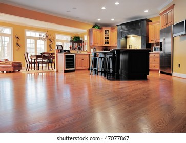 Home Interior Shows A Large Expanse Of Wood Flooring In The Foreground And A Kitchen And Dining Room In The Background. Horizontal Format.