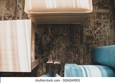 Home Interior Top View Of Foots In Socks, Table And Sofa With Vintage Carpet On Floor. Minimalist Apartment Or Rustic Dwelling, Loft With Cozy Modern Furniture. Indoors Look Of Living Room Or Bedroom