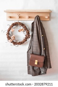 Home interior - a vine wreath, a checkered jacket, a bag on a wooden hanger in the hallway. Autumn mood        