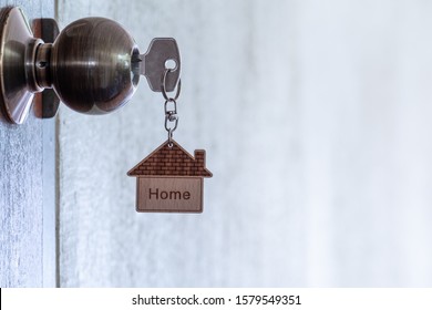 Home key with house keyring in keyhole on wooden door, copy space