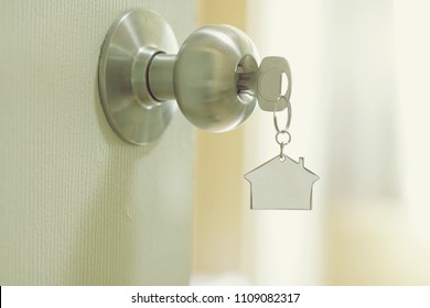 Home key with metal house keychain in keyhole, property concept, copy space
