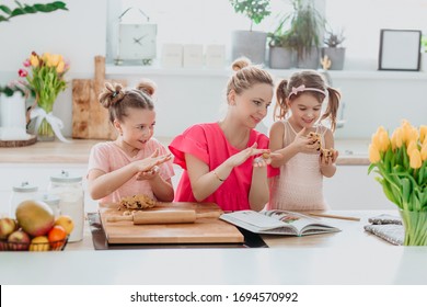 Home kitchen activities - Woman and kids baking cookies, smiling, laughing, having fun. 