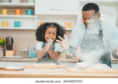 In a home kitchen, black father and his daughter bond over cooking a meal food, their laughter and love filling the air, embodying the joy of African American family life, Father's Day concept - Powered by Shutterstock
